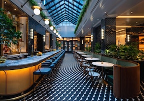 A modern bar area with a long counter, seating, and a patterned floor.