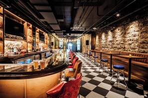 A bar with a checkered floor, bar stools, and a long counter.