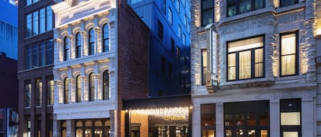Un hôtel à la façade classique, doté de grandes fenêtres et d’une entrée bien éclairée.