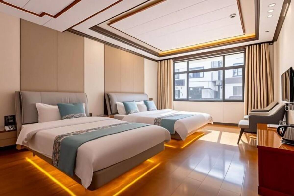 A hotel room with two beds, a TV, and a large window.
