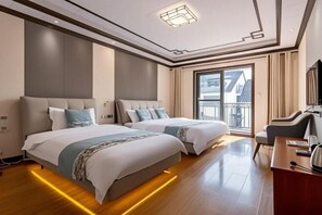 Habitación de hotel con dos camas, un escritorio y un ventanal amplio.