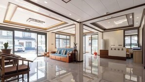A modern hotel lobby with a reception desk, seating area, and large windows. - Zhouzhuang Yuesheng Hotel (Kunshan)