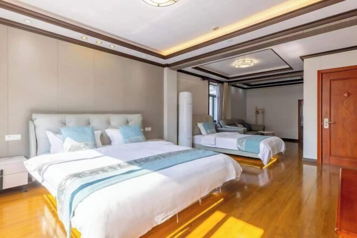 A hotel room with a large bed, a smaller bed, a desk, and a wardrobe.