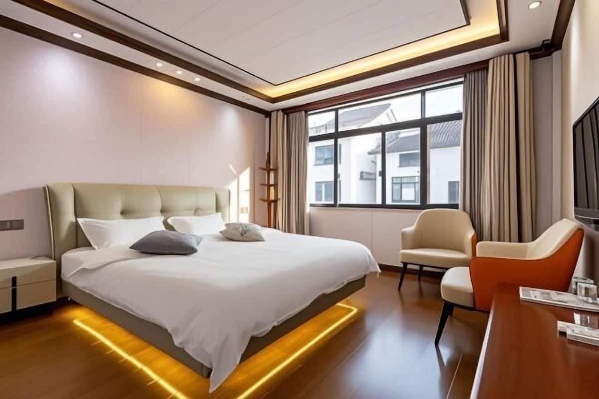 A hotel room with a bed, a desk, a chair, and a window with curtains.