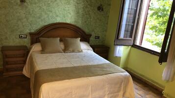 Une chambre à coucher avec un lit en bois, deux tables de chevet, une fenêtre avec des volets et un mur vert à texture.