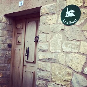Edificio de piedra rústica con puerta de madera y un cartel que indica 'Casa Rural'.