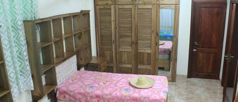 A bedroom with a wooden bed, a wardrobe, and a small bedside table.