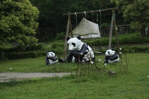 Un recinto de pandas con un columpio de madera y un refugio.