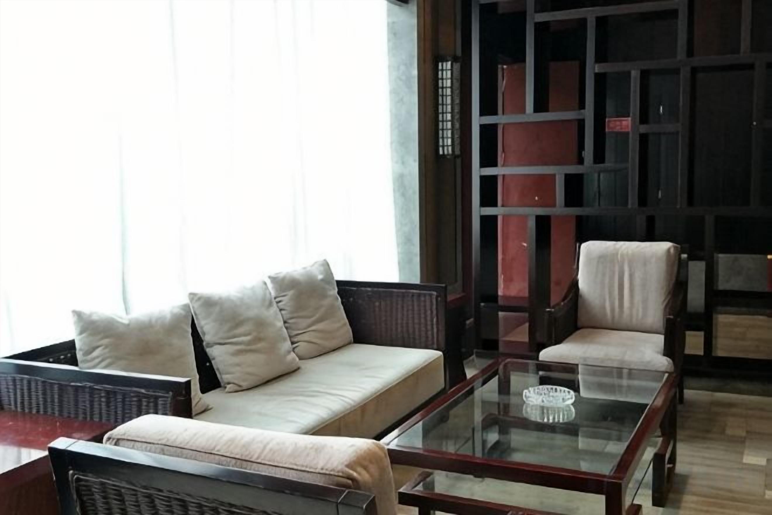 Una habitación con sofá, sillones y una mesa de centro de vidrio.