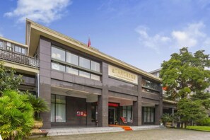 A modern hotel with a two-story structure, a covered entrance, and a landscaped front yard.
