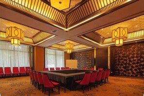 A conference room with a long table, red chairs, and patterned carpet.
