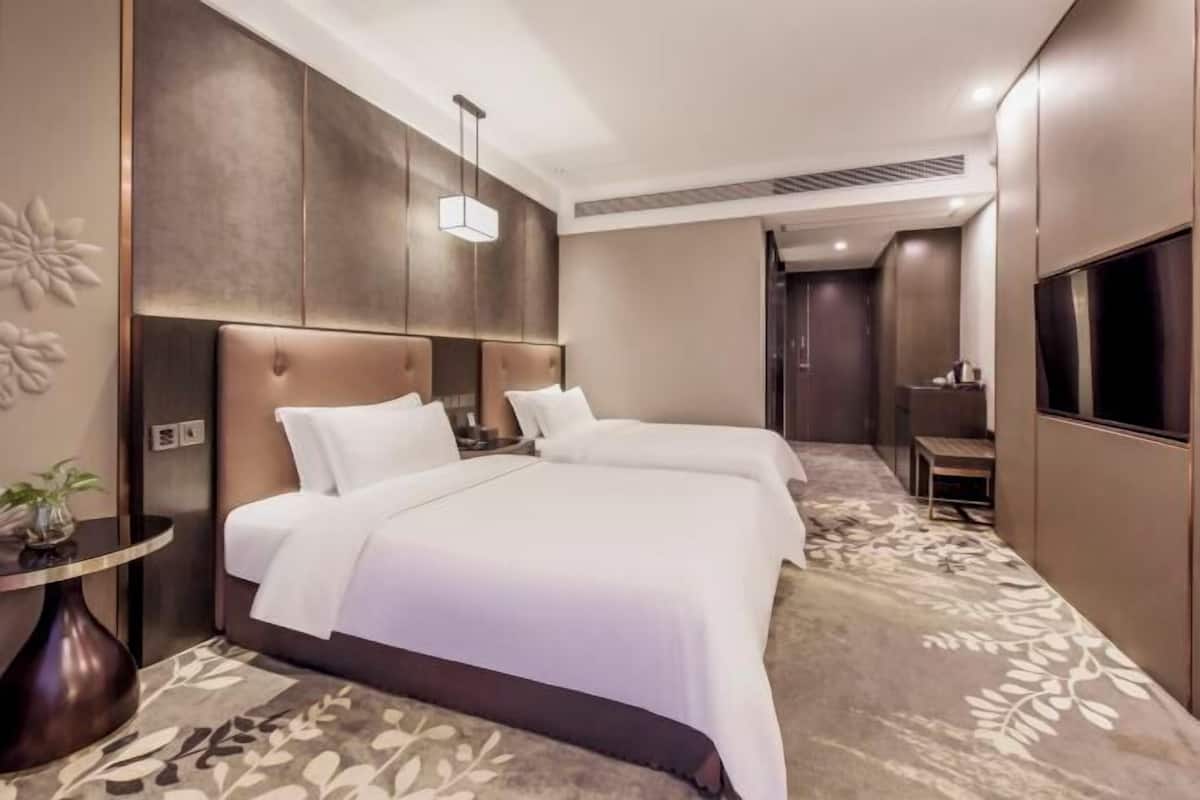 A hotel room with two beds, a round table, and a TV.