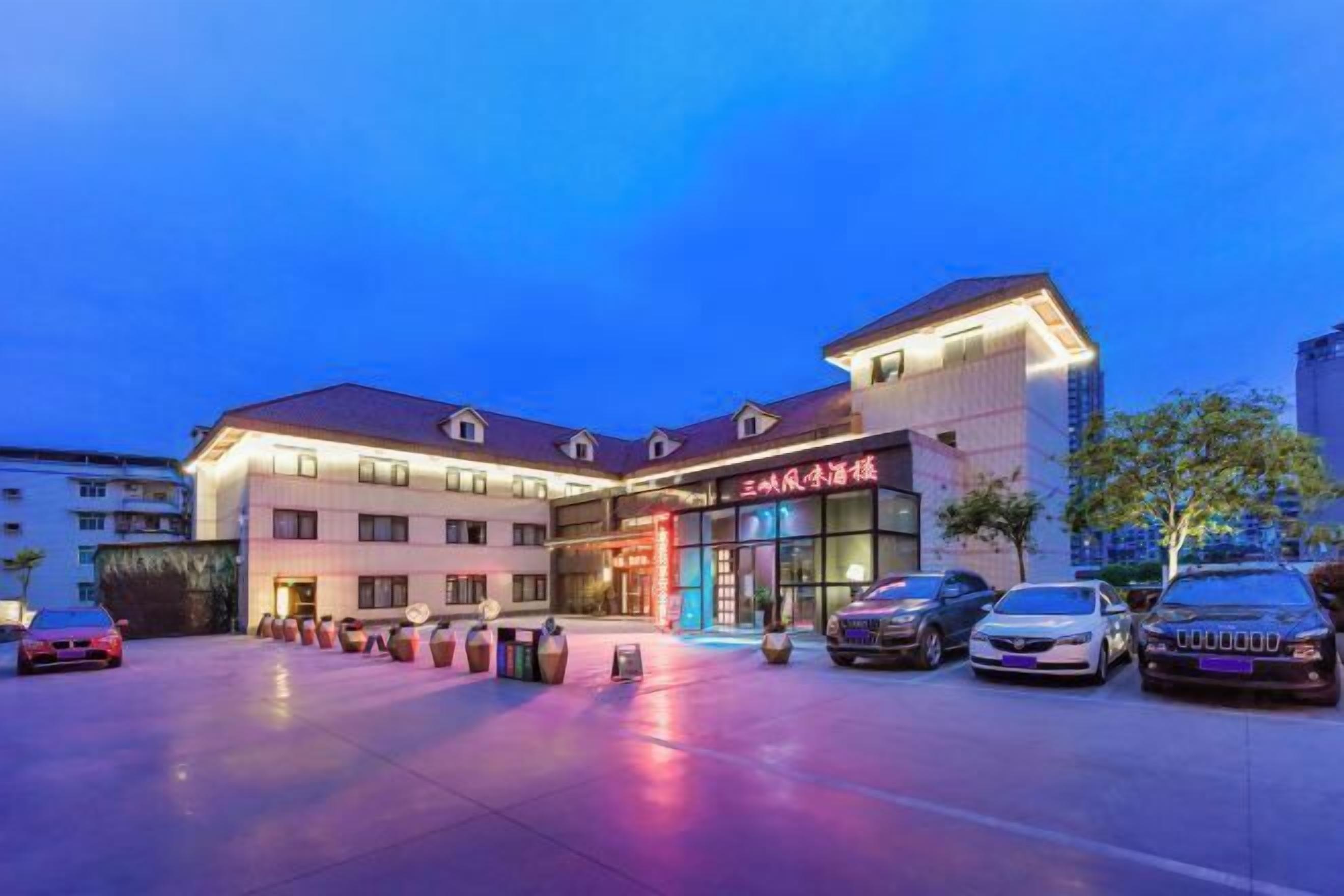 A hotel with a modern facade, multiple parking spaces, and a well-lit entrance.