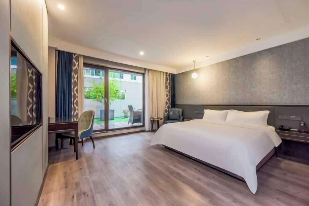 A modern hotel room with a large bed, a desk, and a chair.