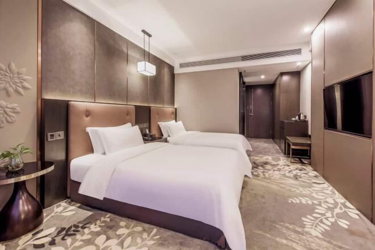 A hotel room with two beds, a round table, and a TV.