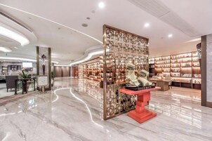 A spacious lobby with a central display, a seating area, and a wall of bookshelves.