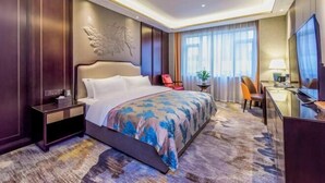 A hotel room with a large bed, a desk, a chair, a TV, and a window with curtains. - San Xia Feng Hotel (Yunyang County)