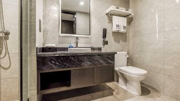 A modern bathroom with a marble sink, a toilet, and a glass-enclosed shower.