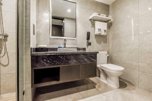 Un baño moderno con lavamanos de mármol, inodoro y ducha con cerramiento de vidrio.