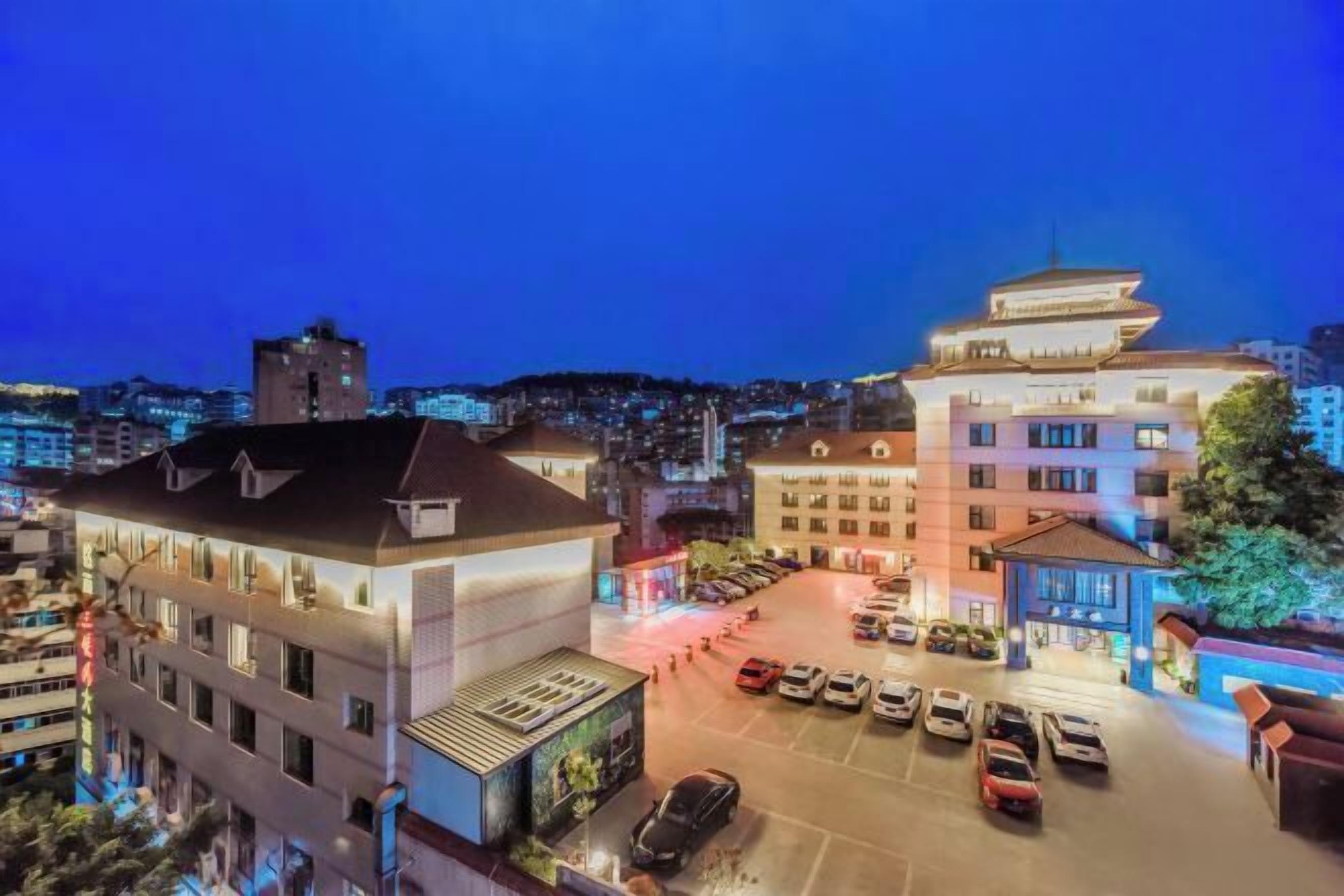 A hotel with a parking lot, a multi-story building, and a traditional pagoda-style structure.