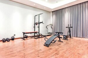 Une salle de sport équipée de matériel d’exercice, notamment un banc, un banc de musculation et des appareils de cardio.