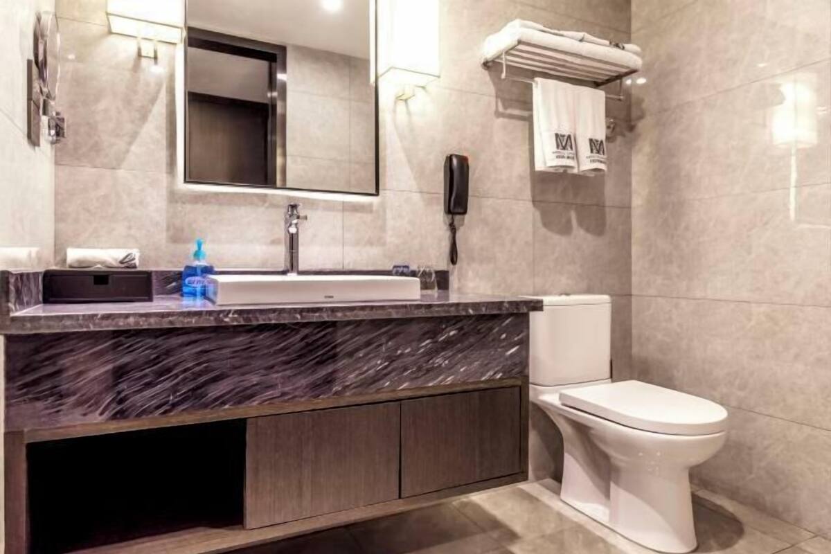 A modern bathroom with a marble sink, a toilet, and a mirror.