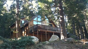Une cabane dotée d’un balcon, entourée d’arbres et de rochers.