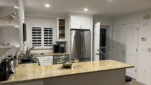 A modern kitchen with white cabinets, a stainless steel refrigerator, and a granite countertop. - Spectacular Boca Grande Waterfront Views of Gasparilla Sound; Boca Grande Club (Boca Grande)