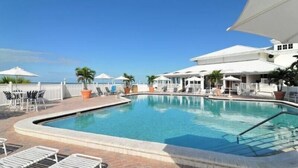 A pool area with lounge chairs, umbrellas, and a view of the ocean. - Spectacular Boca Grande Waterfront Views of Gasparilla Sound; Boca Grande Club (Boca Grande)