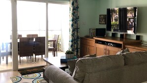 A living room with a grey sofa, a TV, and a ceiling fan.