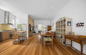A spacious kitchen with wooden flooring, a dining area with a large table, and a living room with a fireplace. - ROSE COTTAGE SORRENTO | WALK TO BEACH & VILLAGE | FAMILY & COUPLES ESCAPE (Sorrento)
