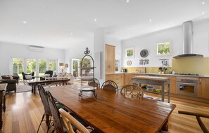 A spacious living area with a wooden dining table, comfortable seating, and a kitchen with modern appliances. - ROSE COTTAGE SORRENTO | WALK TO BEACH & VILLAGE | FAMILY & COUPLES ESCAPE (Sorrento)