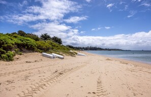 A sandy beach with footprints, a white boat, and a forested area in the background. - ROSE COTTAGE SORRENTO | WALK TO BEACH & VILLAGE | FAMILY & COUPLES ESCAPE (Sorrento)