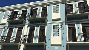 Un edificio a più piani con balconi, un cartello con il numero civico e un cancello.
