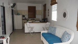 Un ambiente compatto con angolo cottura, un divano con cuscini decorati e una zona pranzo.