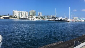 Una marina con diversi yacht ormeggiati, un ampio edificio bianco e un ponte sullo sfondo.