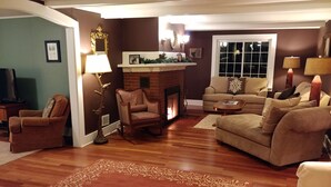 A living room with a fireplace, a sofa, a chair, and a coffee table. - Maple View House, 3 fireplaces, sauna, game room, 4 living rooms, 4 TVs, grill (North Conway)