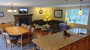 A spacious living area with a fireplace, a dining table, and a kitchen with granite countertops. - Maple View House, 3 fireplaces, sauna, game room, 4 living rooms, 4 TVs, grill (North Conway)