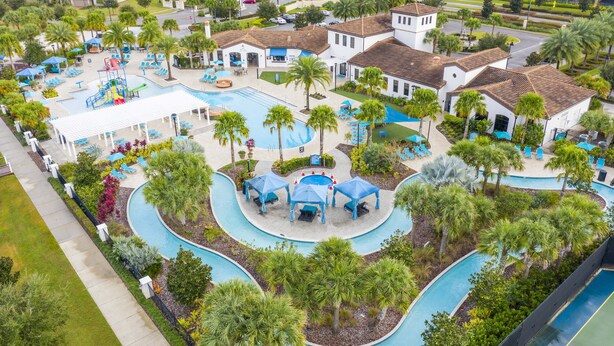 Eine Luftaufnahme eines Resorts mit mehreren Schwimmbecken, Palmen und einem Spielplatz.