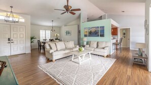 Uma sala de estar espaçosa, com um amplo sofá, uma mesa de centro e um ventilador de teto.