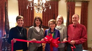 A group of people holding a red ribbon in a room with a chandelier and curtains. - Legacy Suite on Main St in central downtown, jacuzzi tub, ask about Wine Tours!! (Fredericksburg)