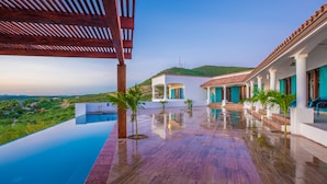 Una villa lujosa con piscina infinita privada, un patio cubierto y vistas del paisaje circundante.