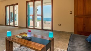 Una habitación amplia con una mesa de centro de madera, dos velas azules y una revista.