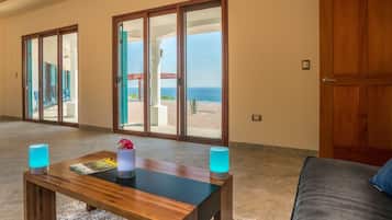 Relax in this stylish living area with a sofa, coffee table, and ocean views through large sliding glass doors.