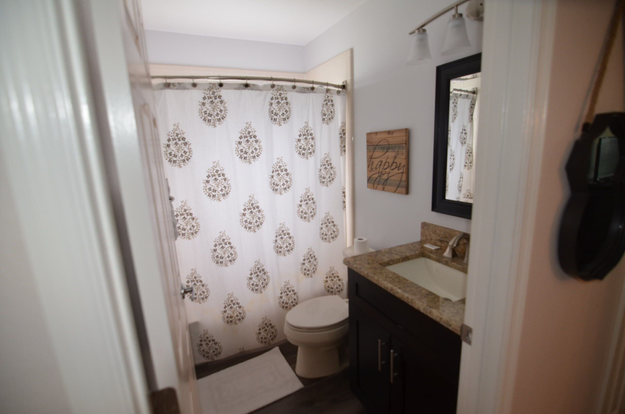 A bathroom with a toilet, sink, and shower curtain.