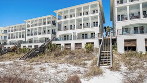 Ett hotell vid stranden med flera balkonger, en central trappa och ett sandstrandområde.