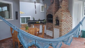 A hammock strung between chairs and a brick oven in a patio area. - House rental in Toque Toque Grande - São Sebastião (North Coast of SP) (São Sebastião)