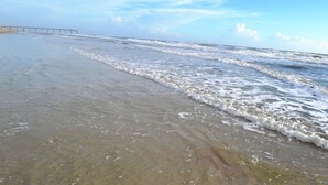 Una playa con un muelle que se adentra en el agua.