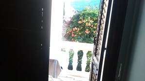 An open door leading to a patio with a stone floor and a view of a garden with flowers and a fence.
