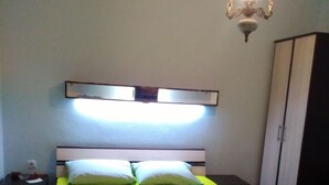 A bed with a green bedspread, two pillows, and a bedside table with a lamp.